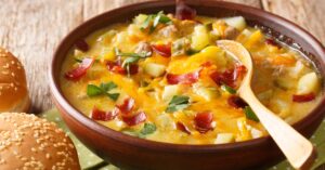 Bowl of Homemade Cheeseburger Soup with Ham and Potatoes Served with Buns