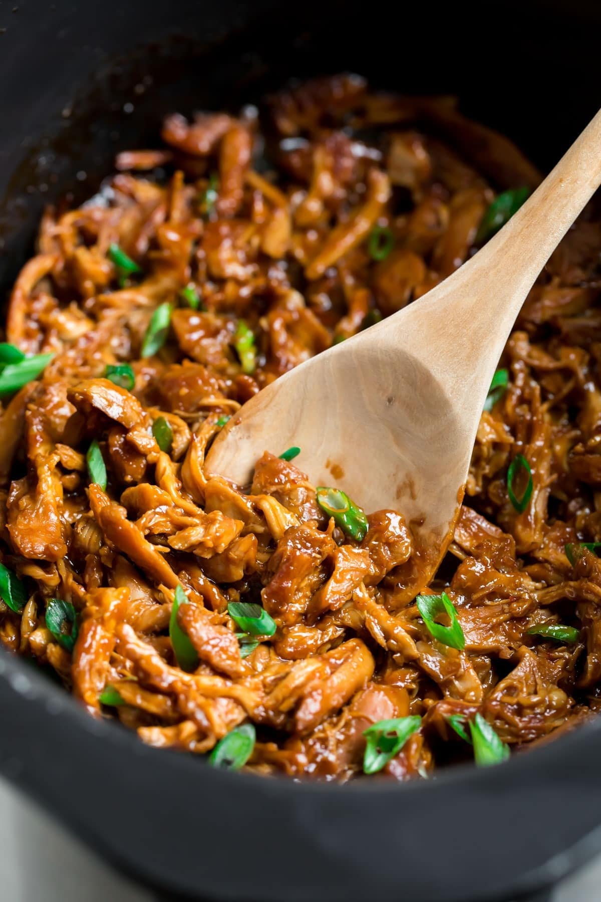 Wooden ladle scooping on Slow Cooker Honey Garlic Chicken